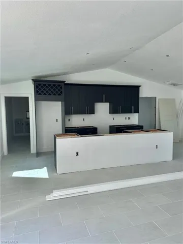 Kitchen featuring lofted ceiling, a large island, light tile patterned floors, and a textured ceiling