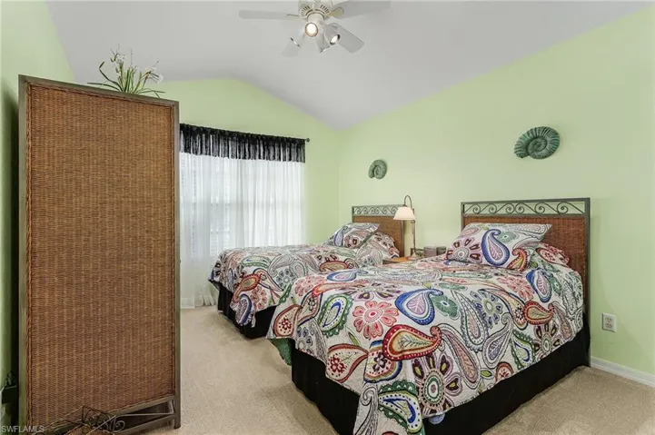 Carpeted bedroom featuring ceiling fan and vaulted ceiling