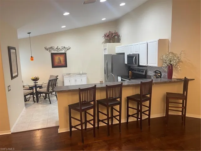 Kitchen featuring kitchen peninsula, stove, a kitchen bar, and fridge