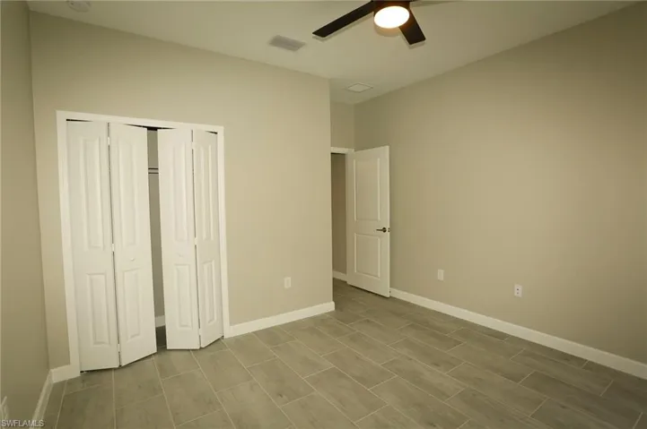 Interior room featuring light-colored walls, contemporary tiled flooring, and a ceiling fan with integrated lighting