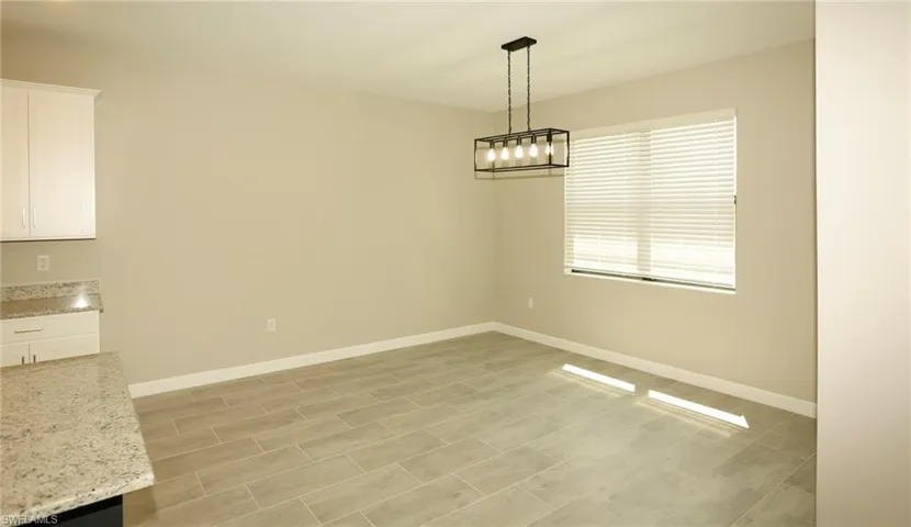 Dining area featuring a modern black linear chandelier, large window with blinds, and tile flooring