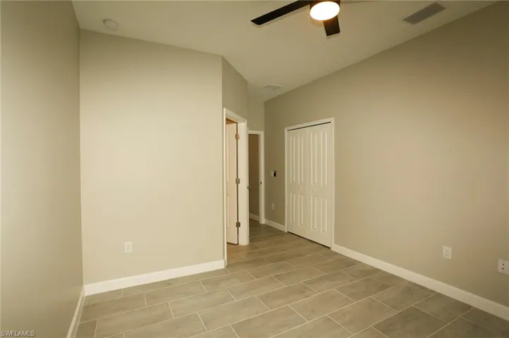 Interior room featuring tile flooring, neutral wall paint, white baseboards, and a ceiling fan with integrated lighting