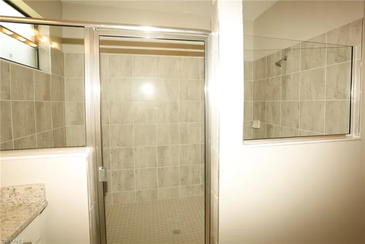 Glass-enclosed shower featuring tiled walls and a tiled floor