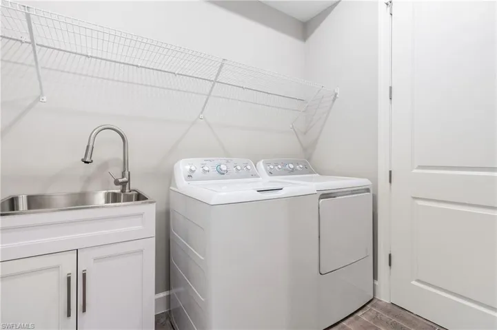 Washroom featuring independent washer and dryer, dark wood finished floors, and cabinet space