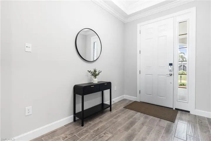 Foyer with ornamental molding and wood finish floors