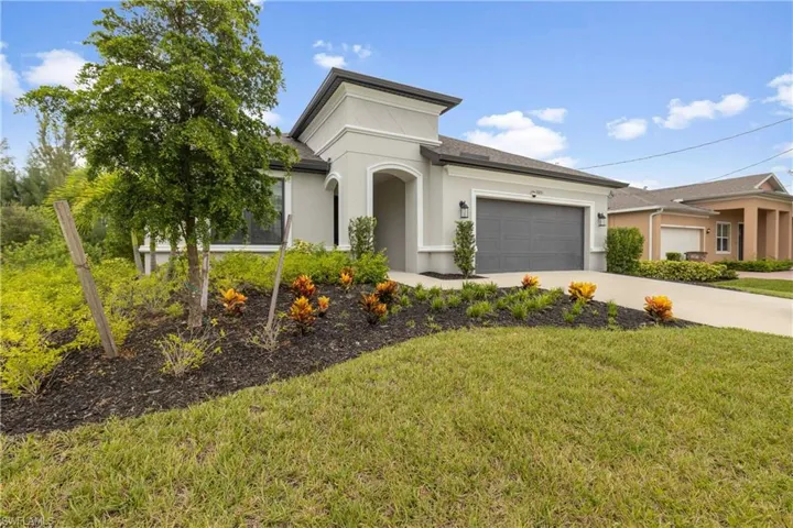 View of front of home featuring concrete driveway, stucco siding, an attached garage, and a front yard
