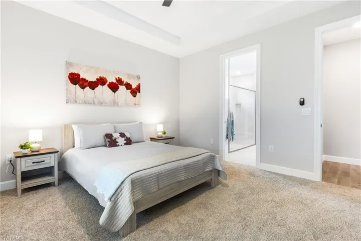 Bedroom featuring light colored carpet, a ceiling fan, and ensuite bathroom
