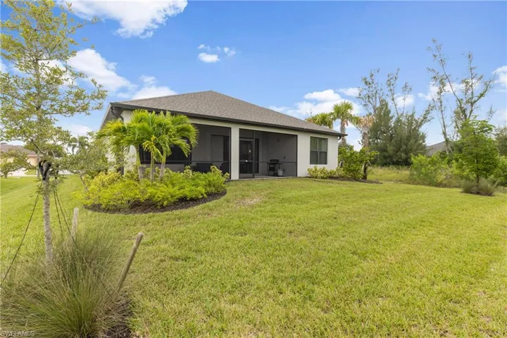 Rear view of house featuring a yard, a sunroom, and roof with shingles