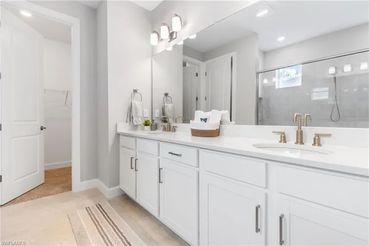 Full bathroom with a stall shower, a spacious closet, double vanity, light tile patterned floors, and recessed lighting