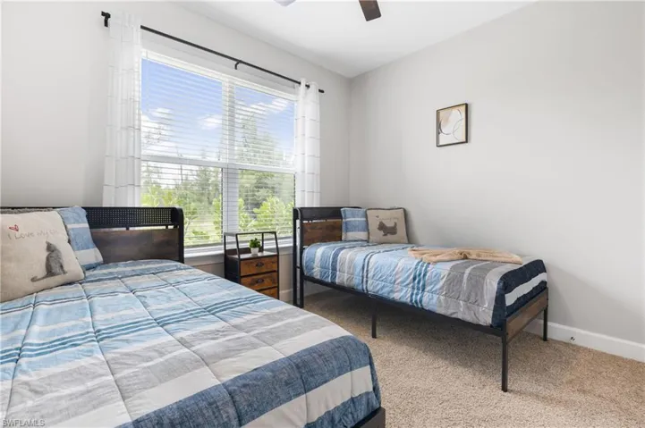 Carpeted bedroom featuring ceiling fan and baseboards
