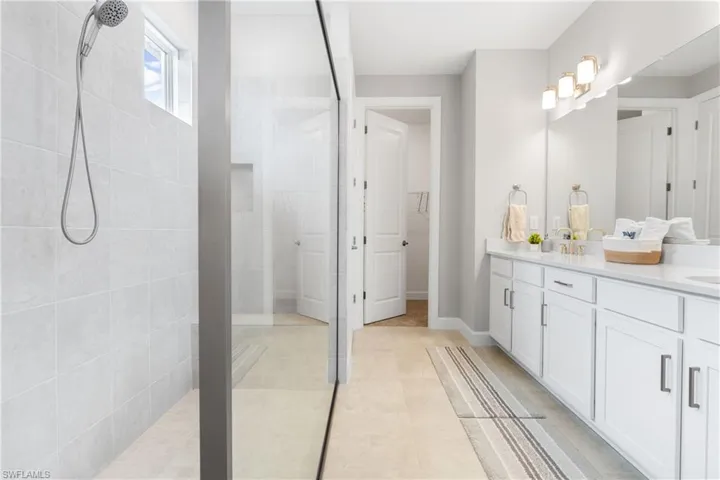 Bathroom with vanity, walk in shower, a walk in closet, and light tile patterned floors