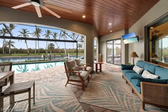 Sunroom with ceiling fan, a swimming pool, a water view, and wood ceiling