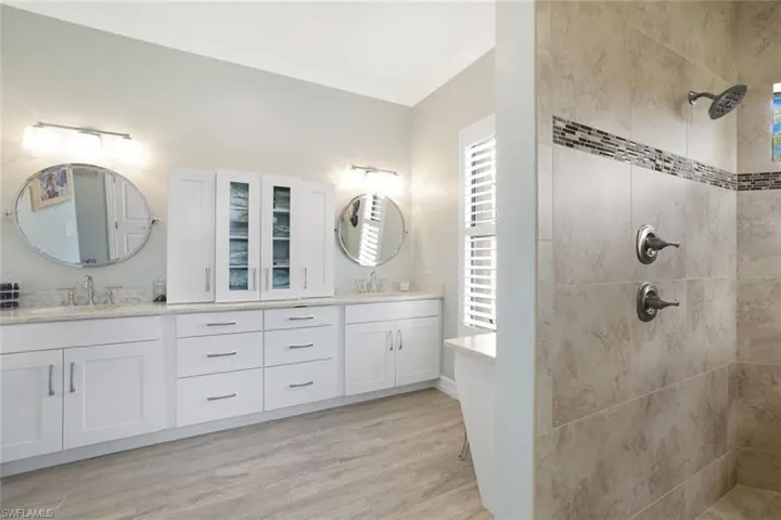 Primary Bathroom with a wealth of natural light, dual bowl vanity, hardwood / wood-style floors, and crown molding