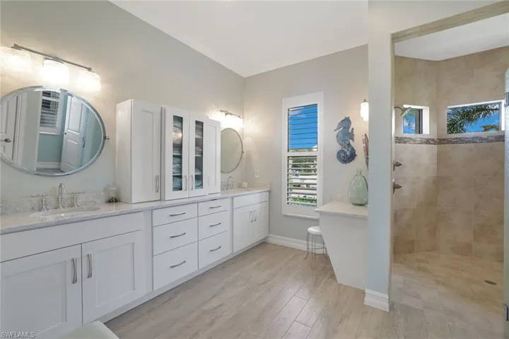 Primary Bathroom with tiled shower, double vanity, ornamental molding, and hardwood / wood-style floors