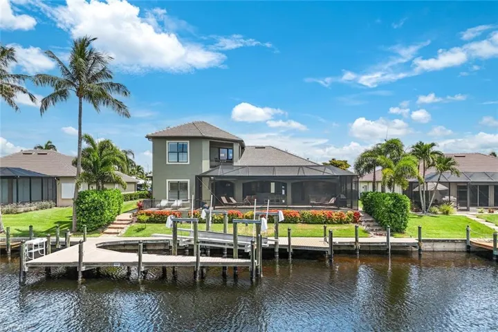 Back of Home Dock area with glass enclosure, a water view, fish house, and a lawn
