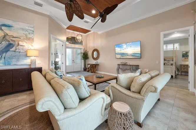 Open Floorplan Living room with french doors, ceiling fan with notable chandelier, and ornamental molding