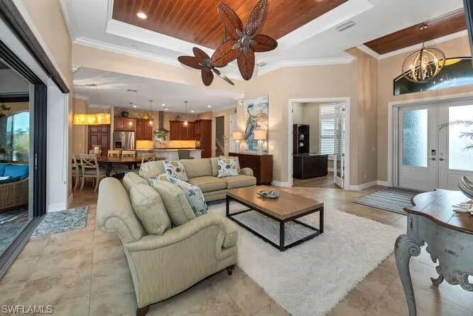Spacious Living room featuring french doors, a tray ceiling, a wealth of natural light, and crown molding
