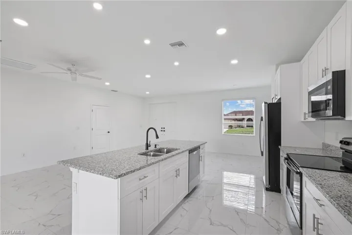 Kitchen featuring ceiling fan, sink, a center island with sink, appliances with stainless steel finishes, and light tile patterned floors
