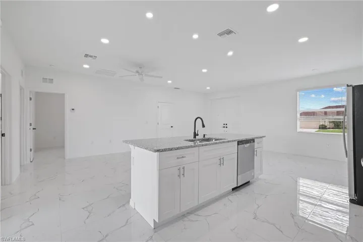 Kitchen featuring light tile patterned floors, appliances with stainless steel finishes, sink, and an island with sink