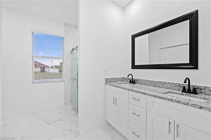 Bathroom featuring double vanity, tile patterned floors, and a shower with shower door