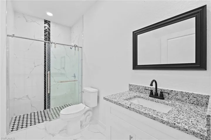 Bathroom featuring toilet, vanity, and an enclosed shower