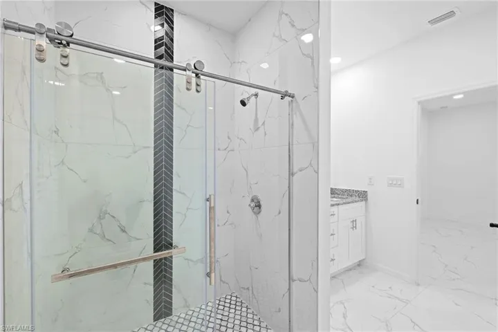 Bathroom with a shower with shower door, vanity, and tile patterned flooring
