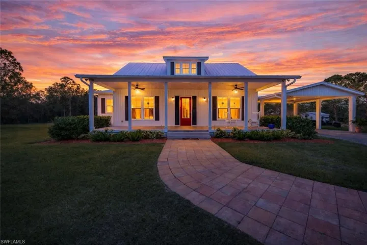 View of front of home featuring ceiling fan, a porch, a lawn, and a metal roof