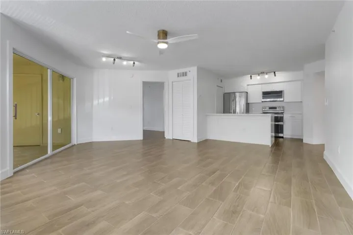 Unfurnished living room with baseboards, light wood-type flooring, track lighting, visible vents, and ceiling fan