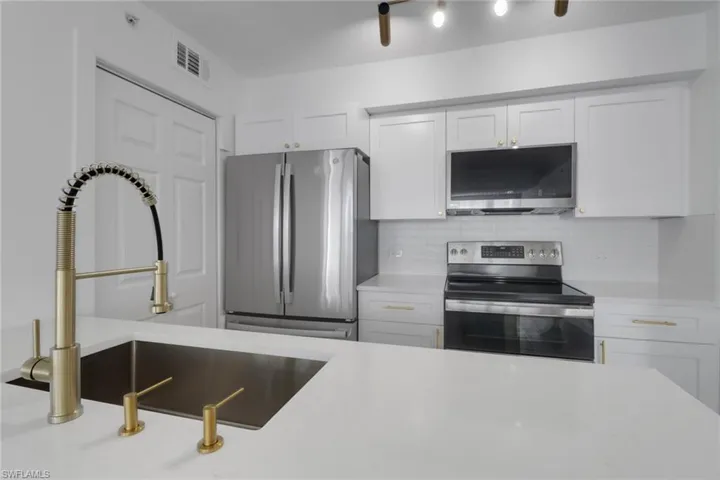 Kitchen featuring tasteful backsplash, a sink, light countertops, white cabinetry, and stainless steel appliances