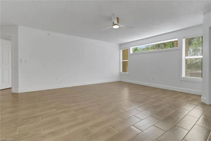 Empty room featuring light wood-type flooring, baseboards, and a ceiling fan