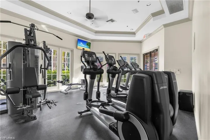 Gym with visible vents, ceiling fan, crown molding, a tray ceiling, and french doors