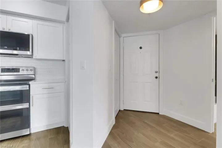 Kitchen featuring white cabinets, light wood-type flooring, baseboards, and appliances with stainless steel finishes