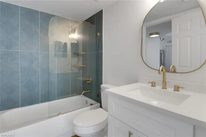 Bathroom with toilet, enclosed tub / shower combo, and vanity