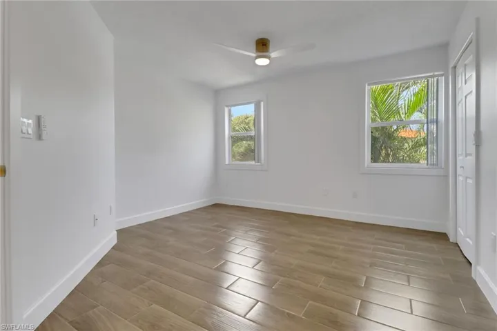 Empty room with light wood finished floors, baseboards, and a ceiling fan