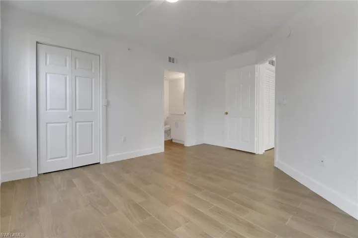 Unfurnished bedroom featuring visible vents, baseboards, a ceiling fan, connected bathroom, and light wood-style flooring