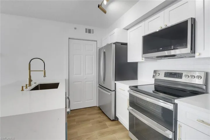 Kitchen with light countertops, white cabinetry, visible vents, stainless steel appliances, and a sink