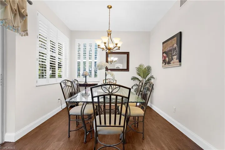 Dining space with dark wood-style floors and a chandelier