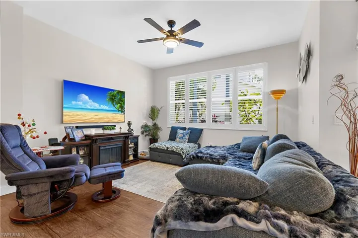 Living area featuring wood finished floors, ceiling fan, and a fireplace
