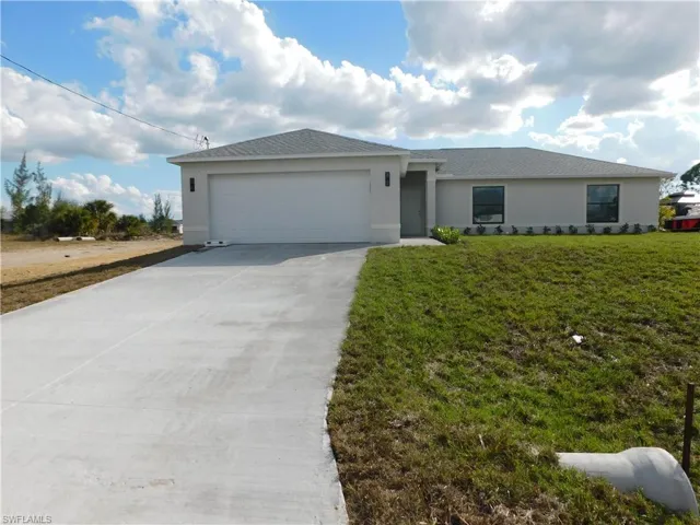 Ranch-style home featuring concrete driveway, stucco siding, a front yard, and an attached garage