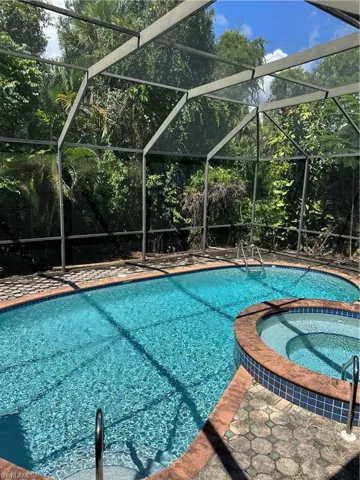 View of pool featuring a pool with connected hot tub, glass enclosure, and a sunroom