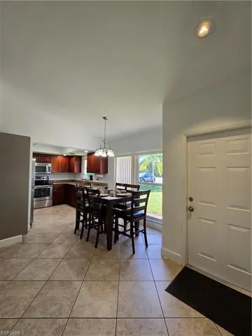 Tiled dining space featuring sink and an inviting chandelier