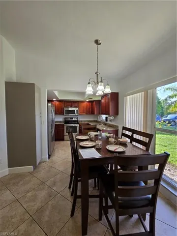 Tiled dining area featuring sink and an inviting chandelier