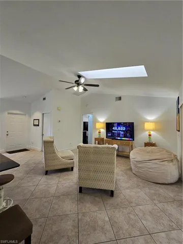 Tiled living room featuring ceiling fan and a skylight