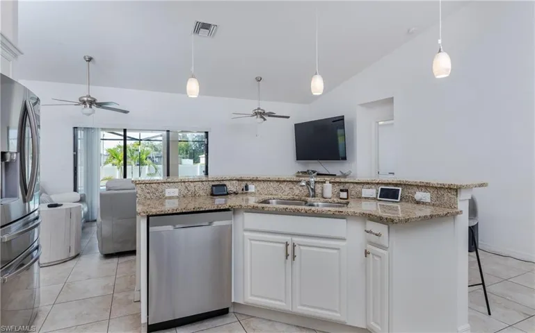 Kitchen featuring granite countertops, stainless steel appliances, white cabinetry, and pendant lighting