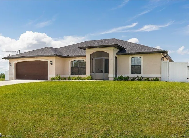 Stucco exterior featuring a screened entry, arched windows, and a brown garage door