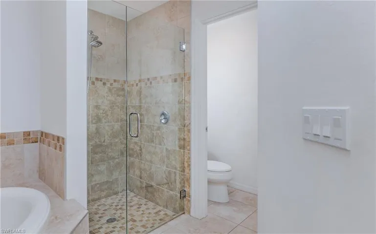 Glass-enclosed shower with full tile surround and mosaic accent band