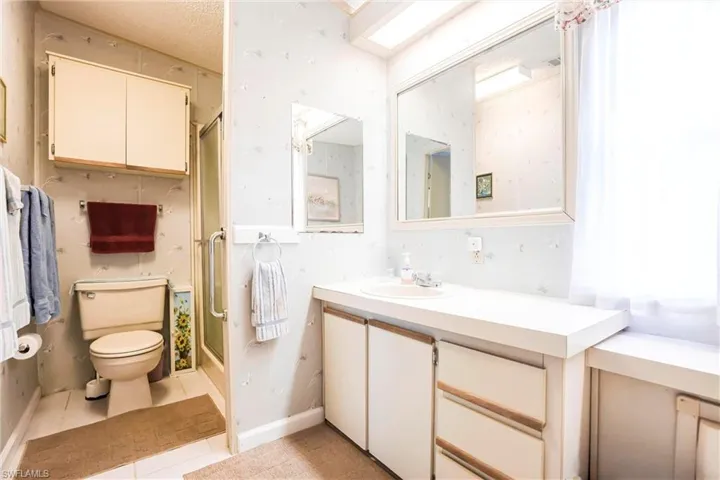 Bathroom with vanity, toilet, tile patterned flooring, and a shower with door