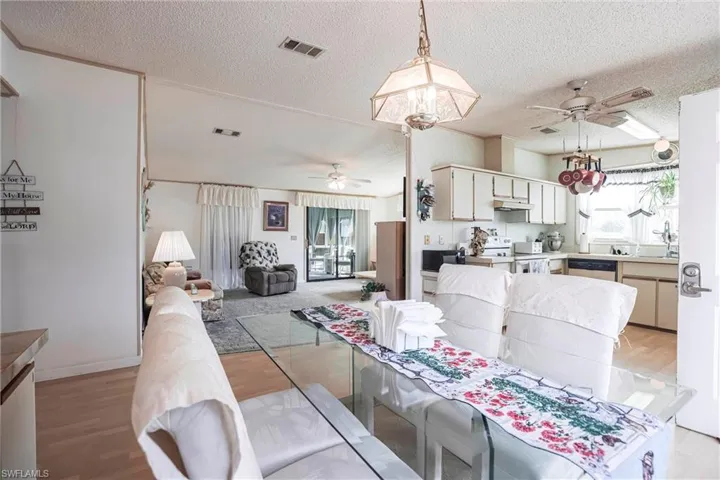 Dining area with ceiling fan, light hardwood / wood-style floors, sink, and a textured ceiling