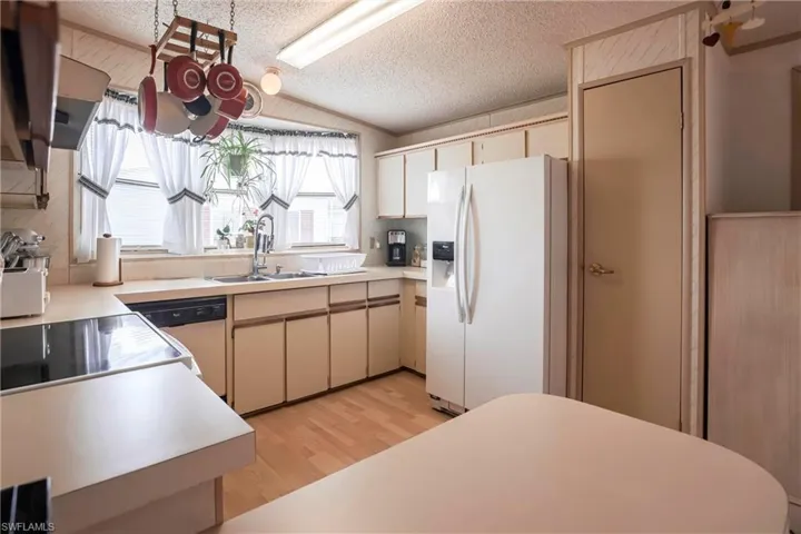 Kitchen featuring sink, white refrigerator with ice dispenser, dishwasher, and cream cabinets