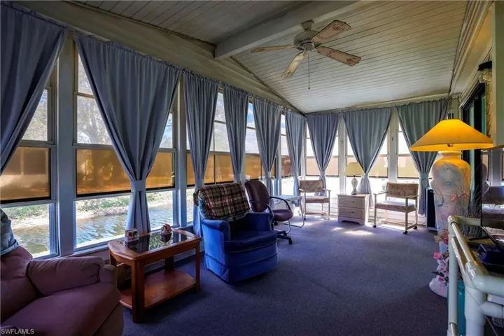 Sunroom / solarium with a water view, plenty of natural light, vaulted ceiling with beams, and ceiling fan